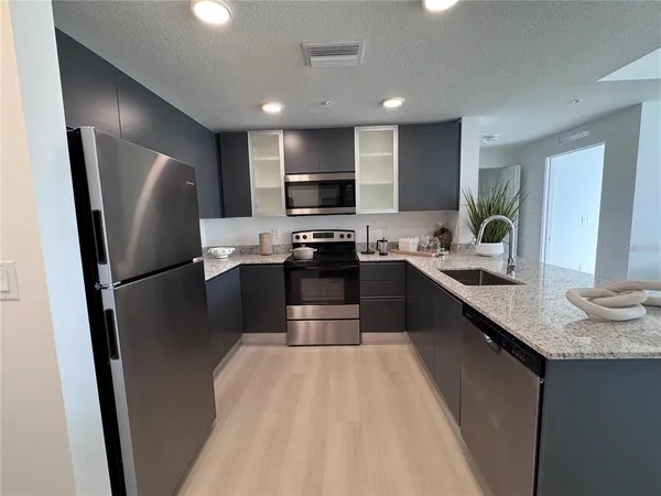 a kitchen with stainless steel appliances a refrigerator a sink a stove a microwave a sink a refrigerator and cabinets