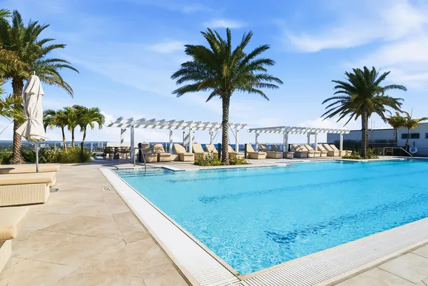 a view of swimming pool with outdoor seating and palm trees