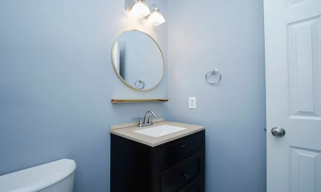a bathroom with a sink vanity mirror and toilet