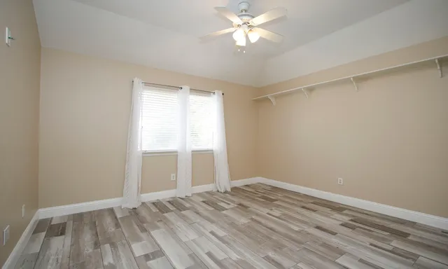 a view of empty room with wooden floor and fan