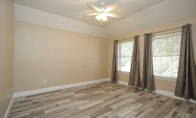 a view of an empty room with window and wooden floor