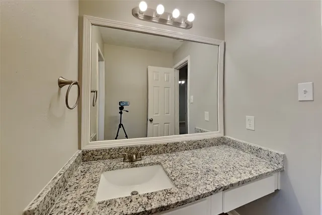 a bathroom with a granite countertop sink and a mirror