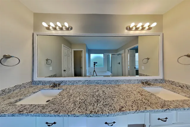 a bathroom with a granite countertop sink and a large mirror