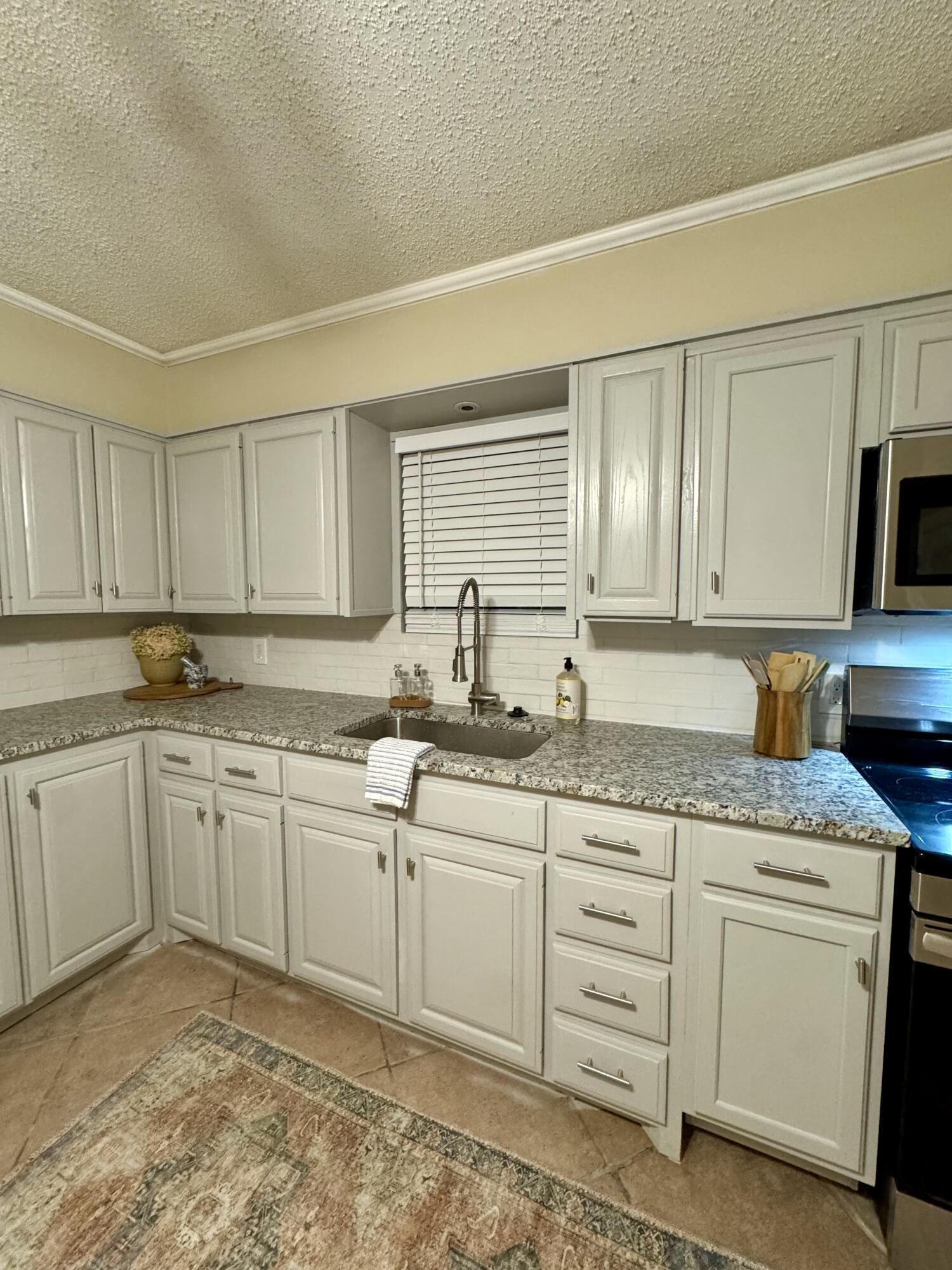 1510 28th Street Lubbock, TX 79411 - Photo 10 of 46 a kitchen with granite countertop white cabinets sink and stainless steel appliances