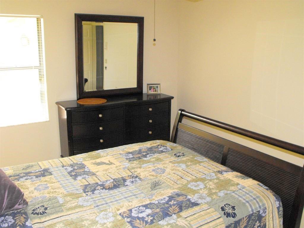 16622 Traders Crossing North, Unit 103 Jupiter, FL 33477 - Photo 11 of 14 a bedroom with a bed and a mirror