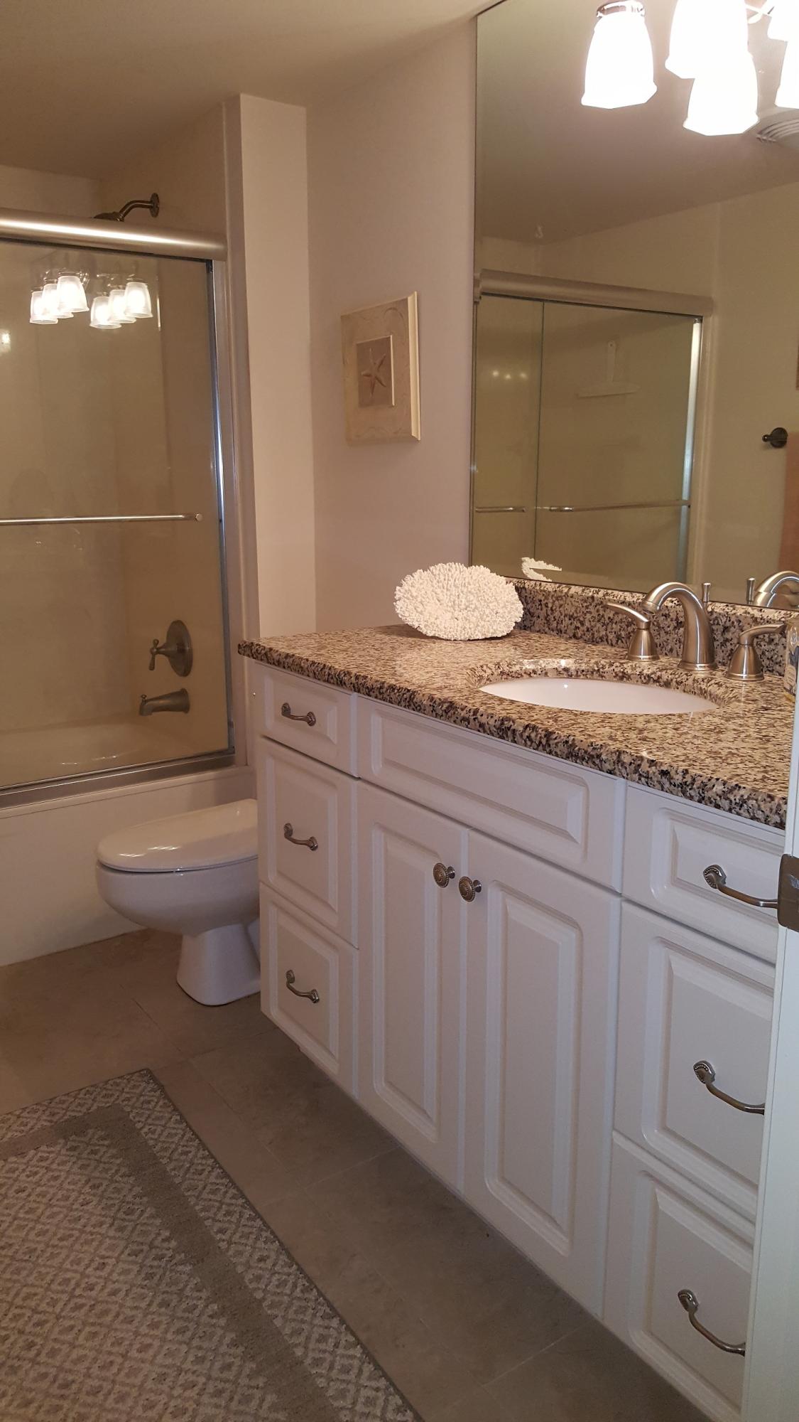 16622 Traders Crossing North, Unit 103 Jupiter, FL 33477 - Photo 12 of 14 a bathroom with a granite countertop sink a toilet and a mirror