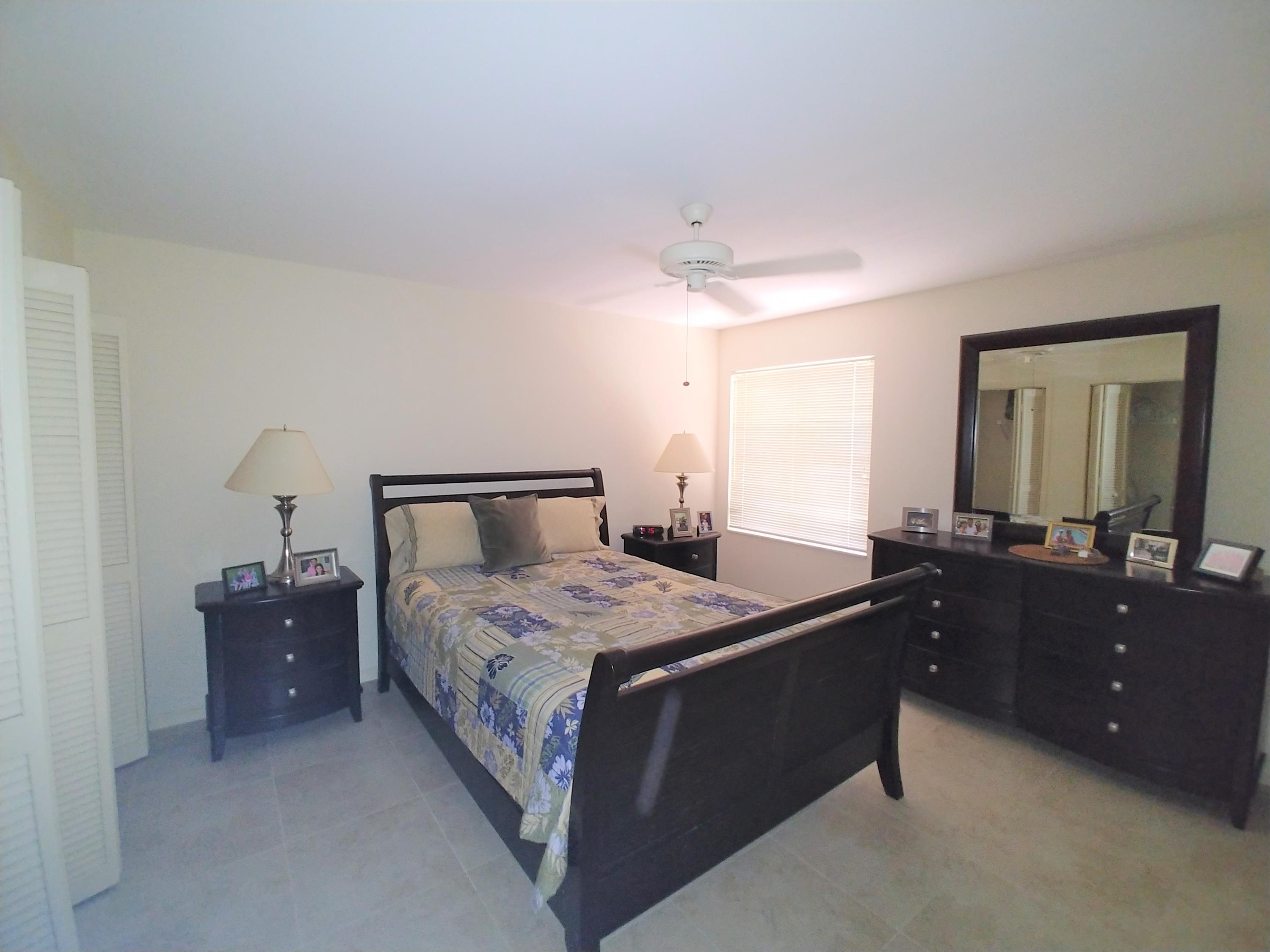 16622 Traders Crossing North, Unit 103 Jupiter, FL 33477 - Photo 10 of 14 a bedroom with a bed and lamp on dresser
