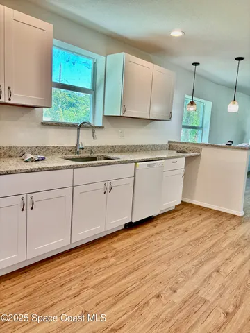 a kitchen with stainless steel appliances granite countertop a sink and cabinets with wooden floor