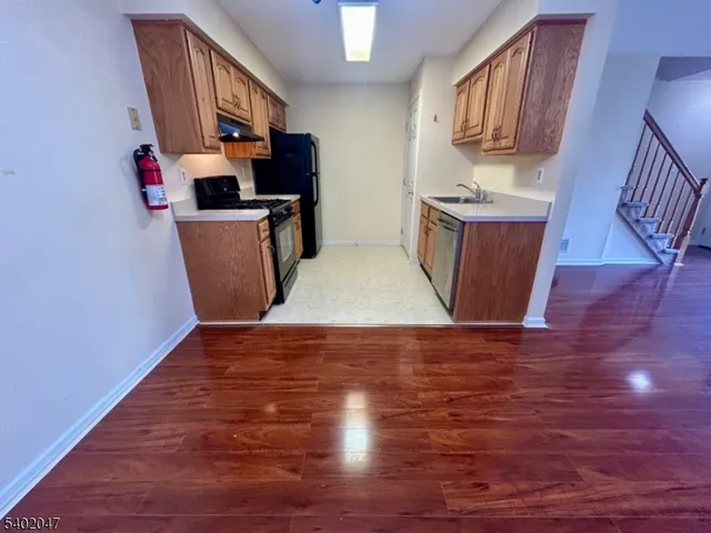 a view of a kitchen with fridge and wooden floor