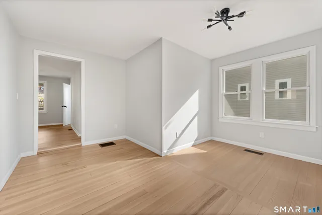 a view of an empty room with a window and wooden floor