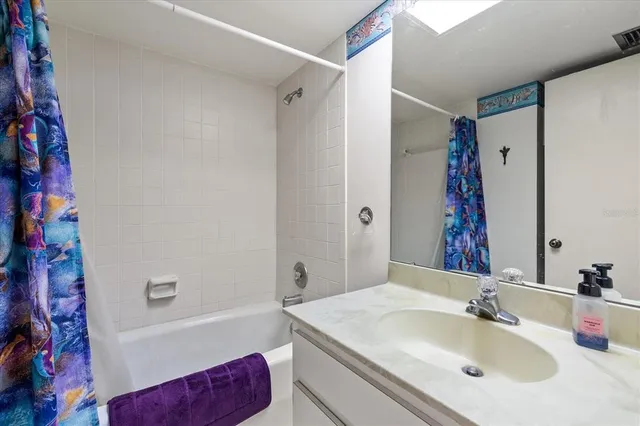 a bathroom with a granite countertop sink mirror and a bath tub