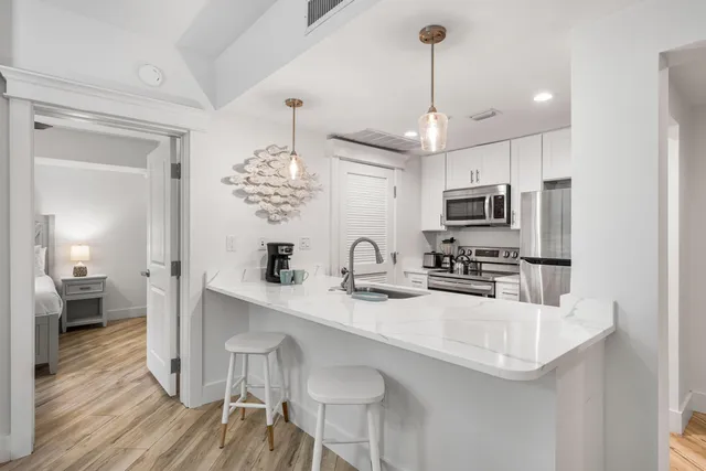 a kitchen with stainless steel appliances granite countertop a sink dishwasher a microwave oven a refrigerator with white cabinets and wooden floor