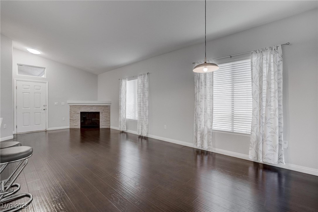 2305 West Horizon Ridge Parkway, Unit 3921 Henderson, NV 89052 - Photo 18 of 31 Unfurnished living room featuring vaulted ceiling, a glass covered fireplace, and wood finished floors