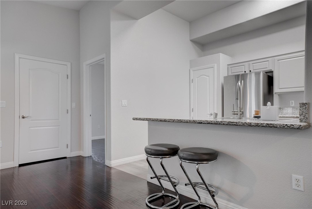 2305 West Horizon Ridge Parkway, Unit 3921 Henderson, NV 89052 - Photo 21 of 31 Kitchen with freestanding refrigerator, a breakfast bar, white cabinets, a peninsula, and wood finished floors