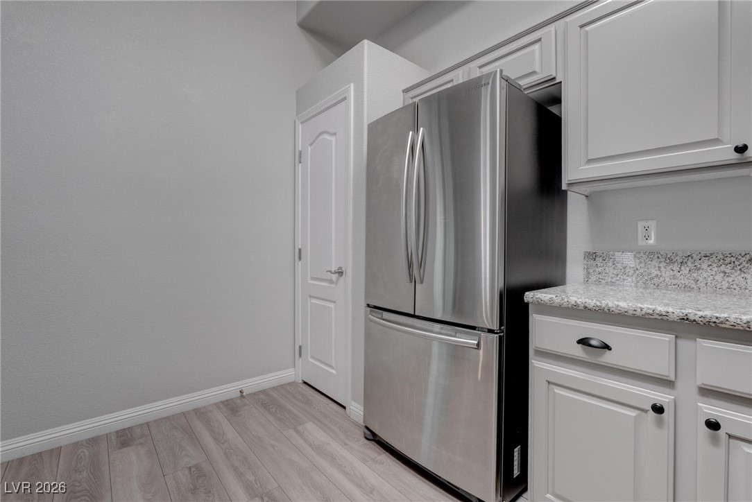 2305 West Horizon Ridge Parkway, Unit 3921 Henderson, NV 89052 - Photo 25 of 31 Kitchen with freestanding refrigerator, light wood-type flooring, white cabinetry, and light stone countertops