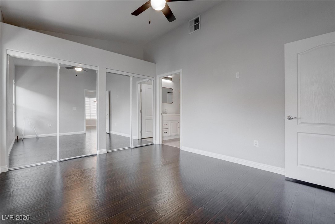 2305 West Horizon Ridge Parkway, Unit 3921 Henderson, NV 89052 - Photo 3 of 31 Unfurnished bedroom featuring lofted ceiling, dark wood-style floors, multiple closets, ceiling fan, and ensuite bath
