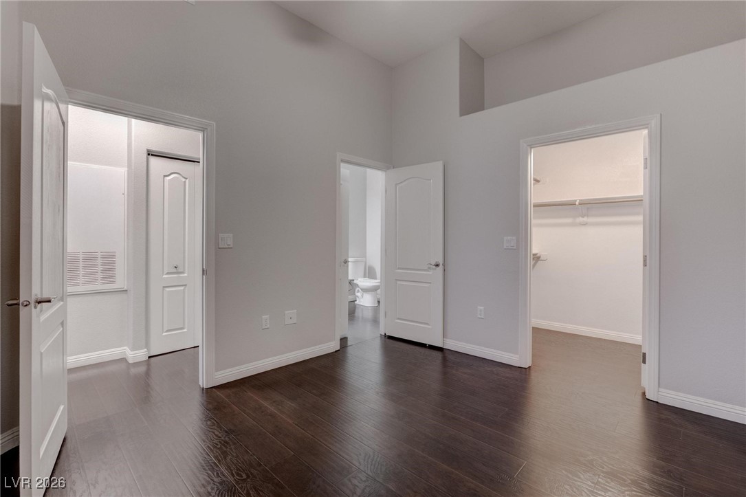 2305 West Horizon Ridge Parkway, Unit 3921 Henderson, NV 89052 - Photo 9 of 31 Unfurnished bedroom featuring dark wood-type flooring, a walk in closet, high vaulted ceiling, and ensuite bathroom