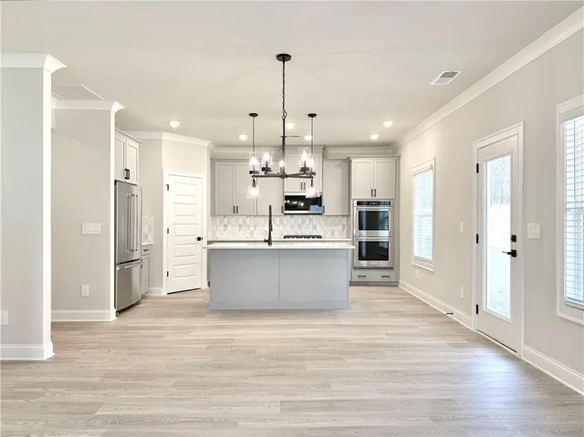 a kitchen with kitchen island a counter top space cabinets and stainless steel appliances