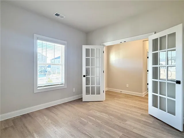 a view of an empty room with wooden floor and windows