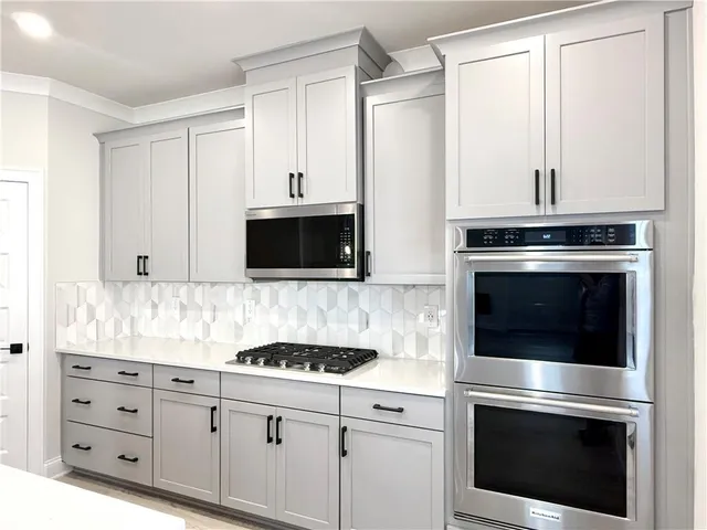 a kitchen with granite countertop white cabinets and stainless steel appliances