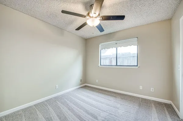 an empty room with a window and a fan