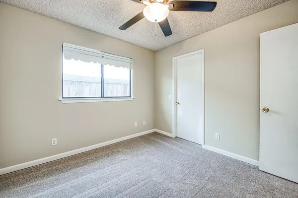 an empty room with a chandelier fan and windows