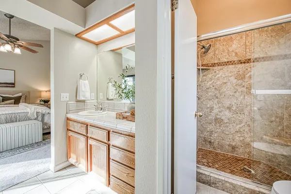 a bathroom with a granite countertop sink a mirror and shower