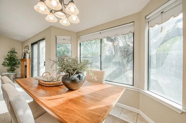 a view of a dining room with furniture a chandelier and large windows