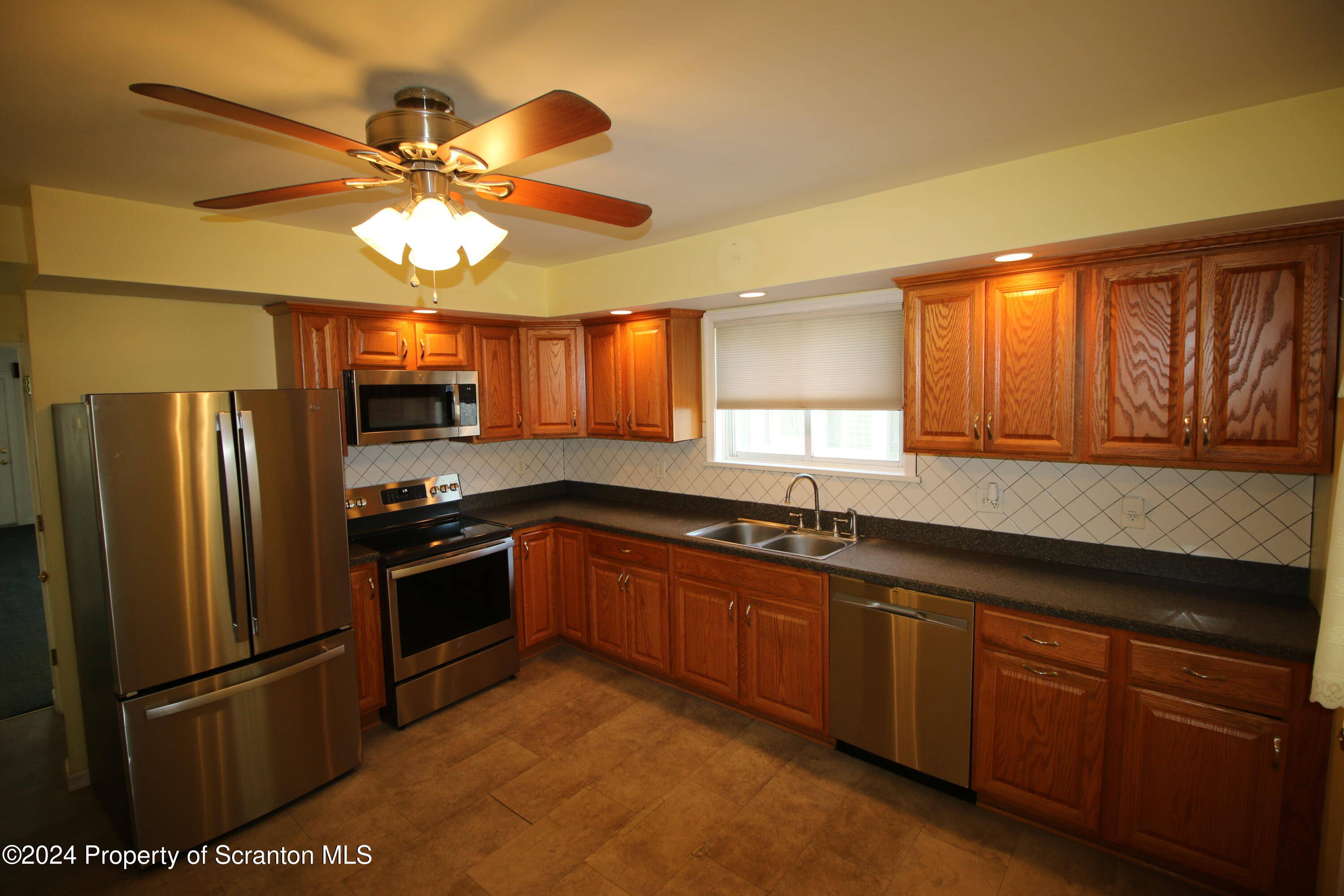 1105 Rundle Street Scranton, PA 18504 - Photo 10 of 30 a kitchen with stainless steel appliances granite countertop a refrigerator a sink dishwasher a stove a dining table and chairs with wooden floor