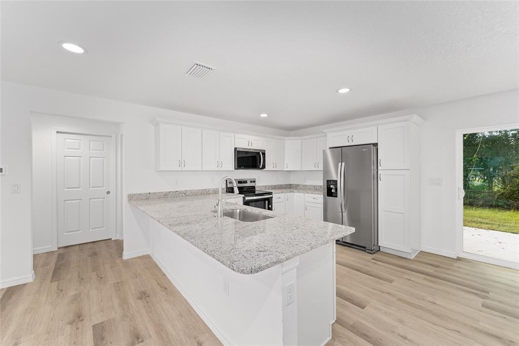 13119 Northeast 7th Loop Silver Springs, FL 34488 - Photo 18 of 51 a kitchen with stainless steel appliances granite countertop a sink dishwasher a refrigerator and a stove with wooden floor