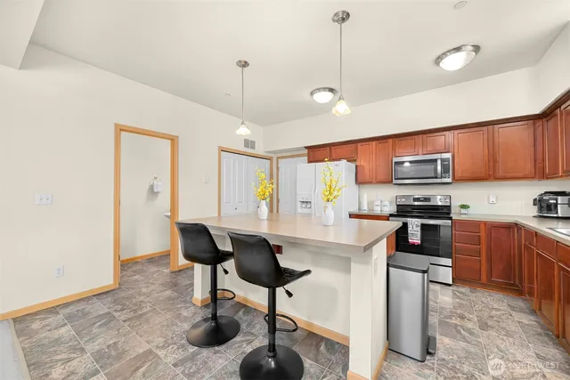 a kitchen with stainless steel appliances granite countertop a stove top oven a sink a dining table and chairs with white cabinets