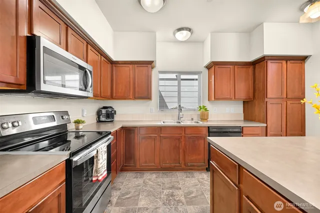 a kitchen with stainless steel appliances granite countertop a sink a stove a microwave cabinets and a counter top space