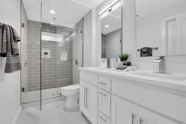a bathroom with a double vanity sink toilet and shower