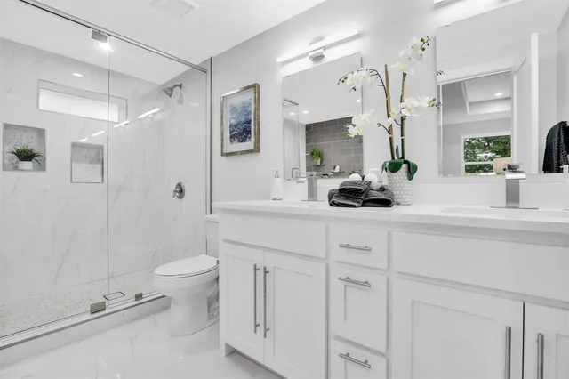 a bathroom with a double vanity sink toilet and shower