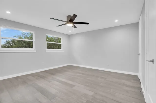 an empty room with windows and fan