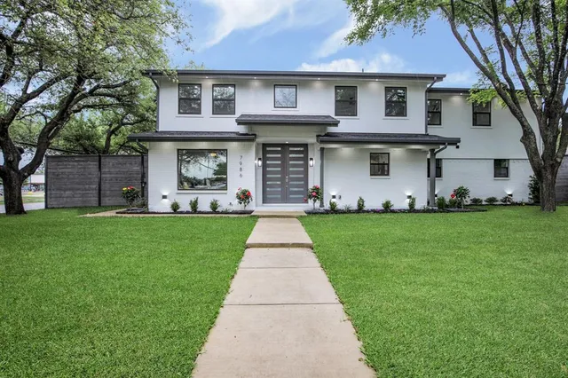 a front view of a house with a garden and plants