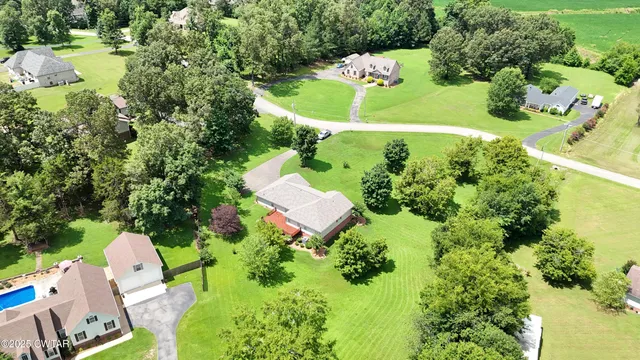 an aerial view of a house with a yard and trees all around