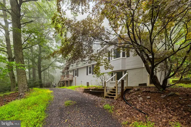 a view of an empty room with wooden floor fireplace and a window