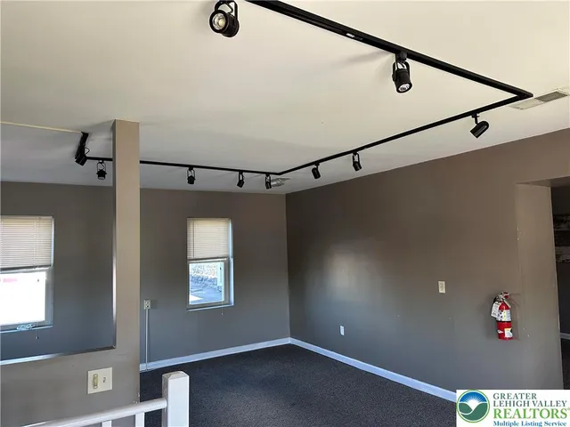 an empty room with windows and fan