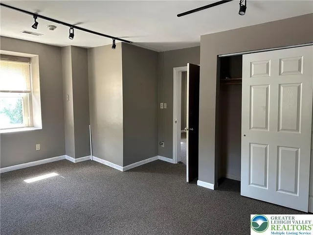 a view of empty room with windows and refrigerator