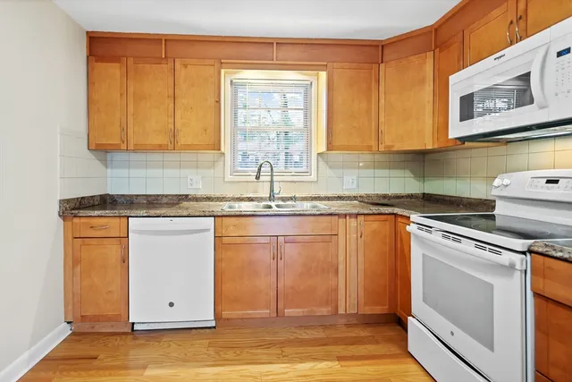 a kitchen with granite countertop cabinets stainless steel appliances a sink and a window