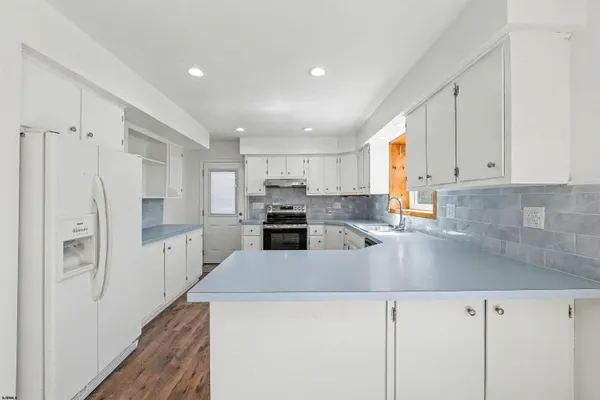 a kitchen with stainless steel appliances granite countertop a refrigerator sink and white cabinets