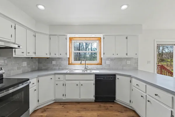 a kitchen with granite countertop white cabinets sink and stainless steel appliances