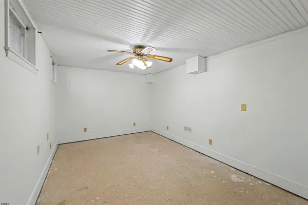 an empty room with a chandelier fan and windows