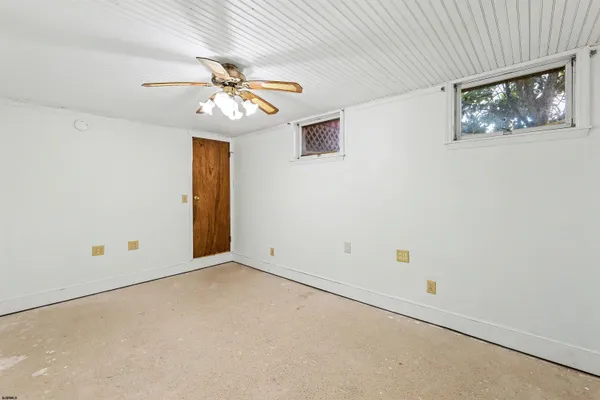 an empty room with a chandelier fan and windows