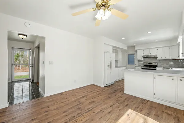 a kitchen with stainless steel appliances granite countertop a refrigerator a sink and white cabinets with wooden floor