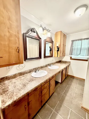 a bathroom with a granite countertop double vanity sink and a mirror