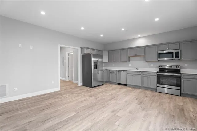 a kitchen with stainless steel appliances granite countertop a refrigerator and a stove top oven