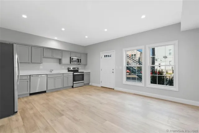 a large white kitchen with kitchen island a sink stainless steel appliances and cabinets