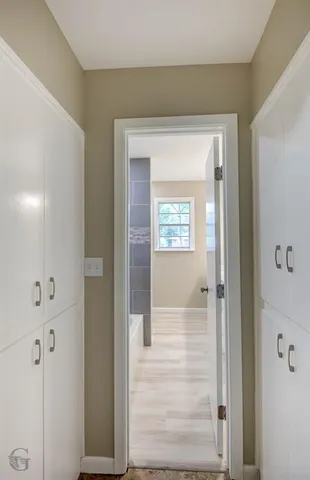 a view of a hallway with a glass door and a bathroom